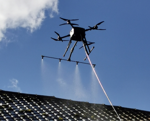 drone équipé d'un système de pulvérisation permettant le démoussage ou le nettoyage des toits