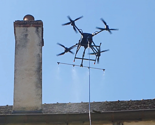 Photographie d'un drone réalisant un démoussage de toiture par drone