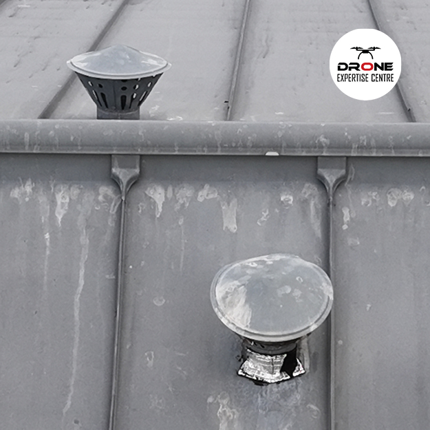 Drone pour inspection toiture examinant une sortie de ventilation