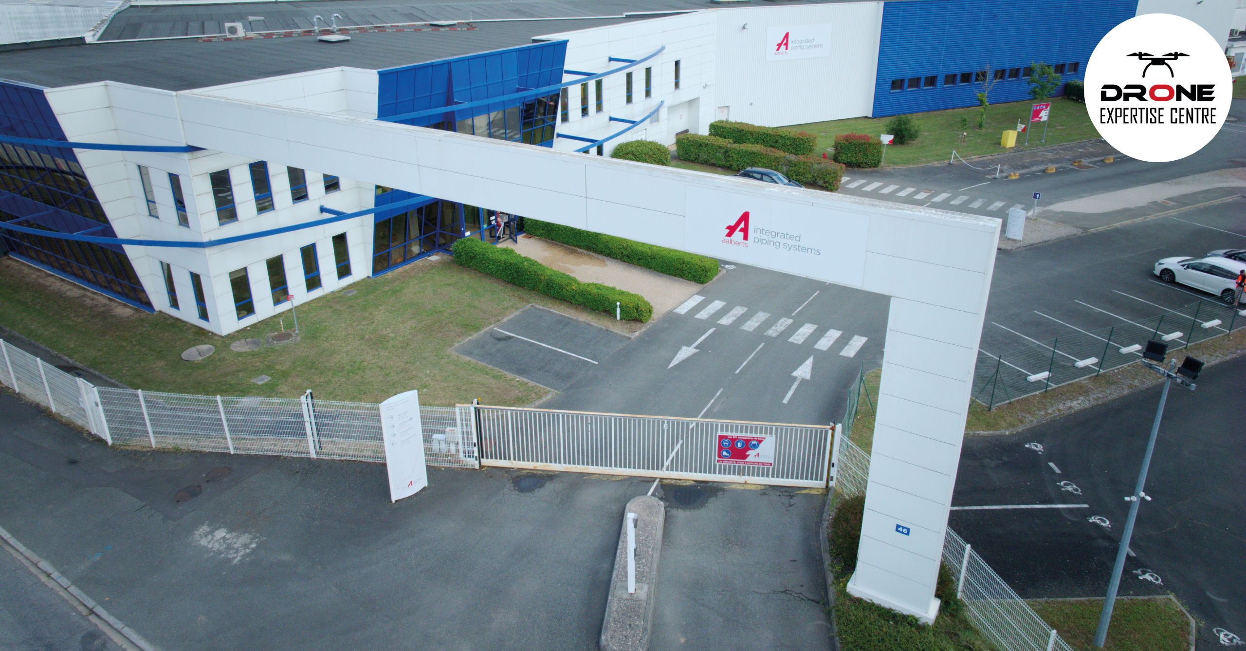 Démoussage par drone de façade appliqué à un grand bâtiment industriel vu en hauteur